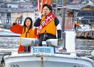 船の上から支持を訴えた上入佐慶太さん（中）＝23日、石川県能登町宇出津で