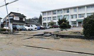 液状化で大きな被害を受けた西荒屋小の校門。右奥は校舎、手前の道路は石川県道松任宇ノ気線＝2024年1月3日、石川県内灘町で（栗田啓右撮影）　