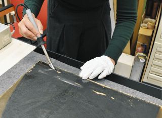 剝がれた絵の具を、接着剤と電気ごてで定着させる＝津市の県立美術館で　
