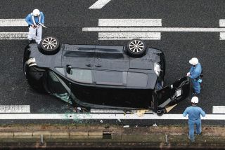事故で横転した乗用車を調べる警察官＝25日午後、岐阜県瑞浪市で、本社ヘリ「わかづる」から