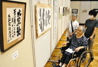 平和への思いが込められた作品を会場で鑑賞する加藤さん（中）ら＝中津川市の中央公民館で