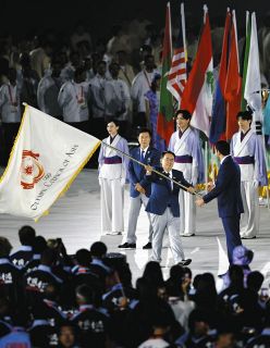 愛知・名古屋アジア大会の閉会式で、OCAのシェイク・ジョアン会長に大会旗を手渡す愛知県の大村秀章知事（中央）。組織委員会は、OCAとの交渉に苦慮してきた＝4日、名古屋市瑞穂区のパロマ瑞穂スタジアムで
